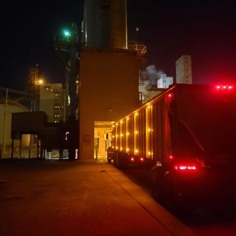 Nighttime truck at illuminated industrial facility entrance.