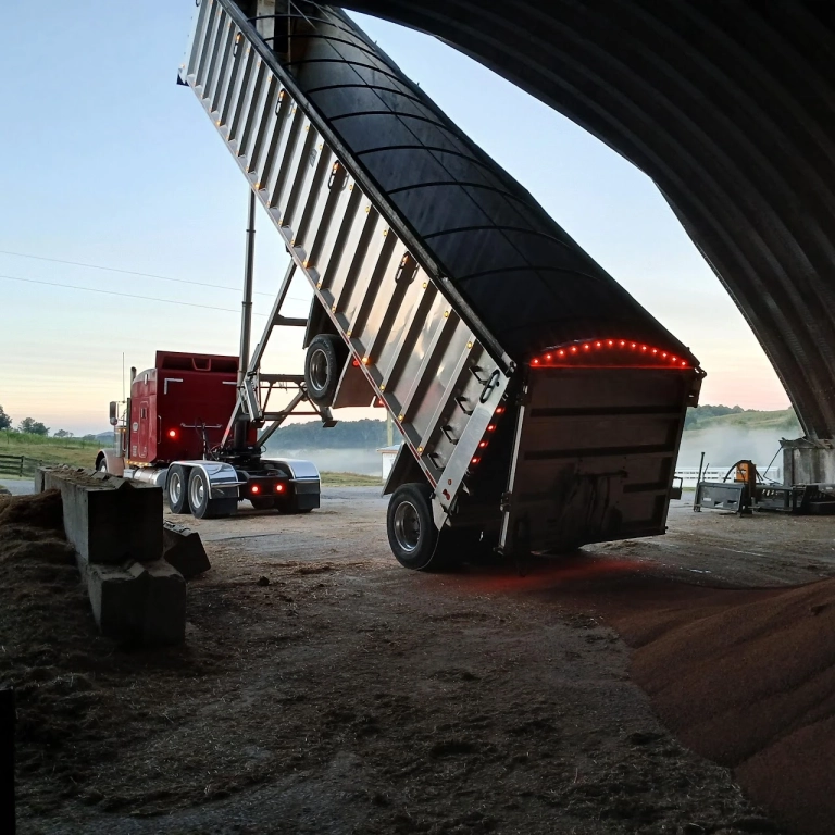 Red truck unloading grain in barn