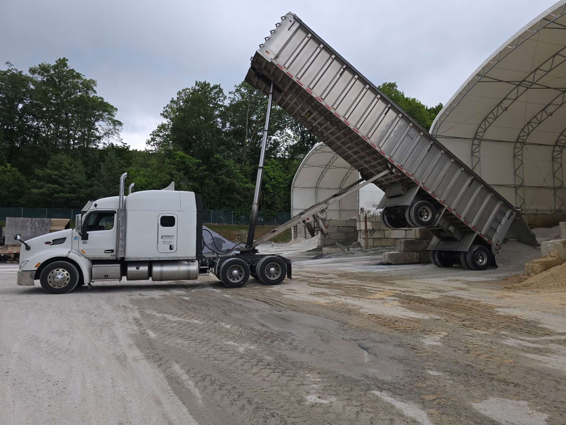 Dump truck unloading sand at construction site.