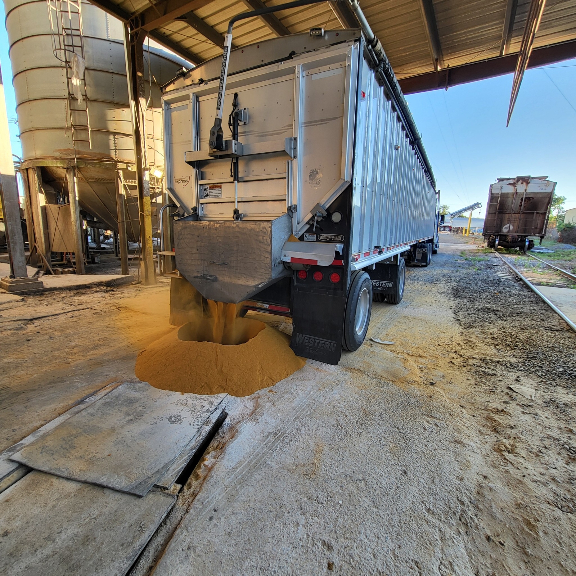 Truck unloading grains in warehouse.