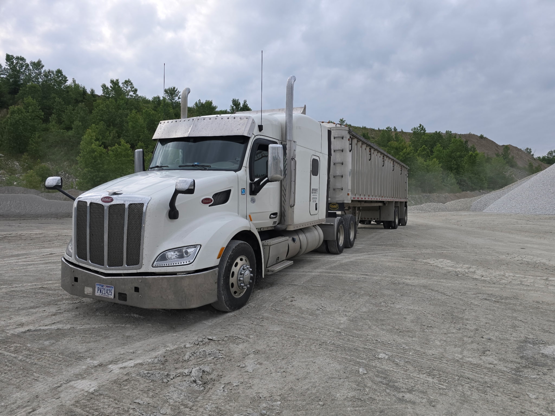 White semi-truck parked in gravel lot.