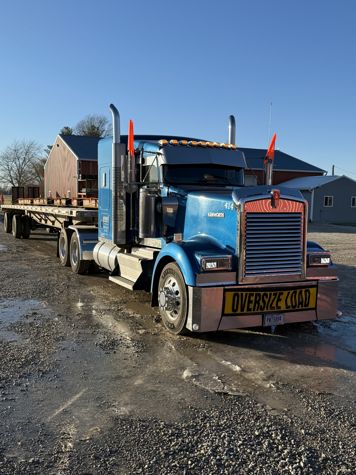 Blue semi-truck with oversize load on trailer.