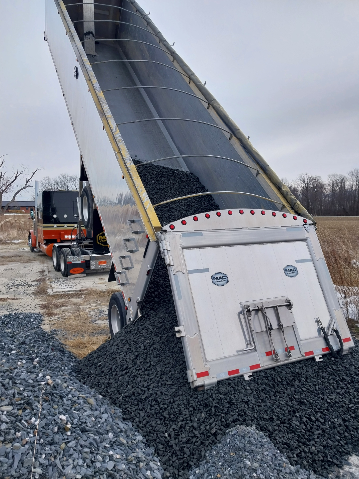 Dump truck unloading black gravel pile