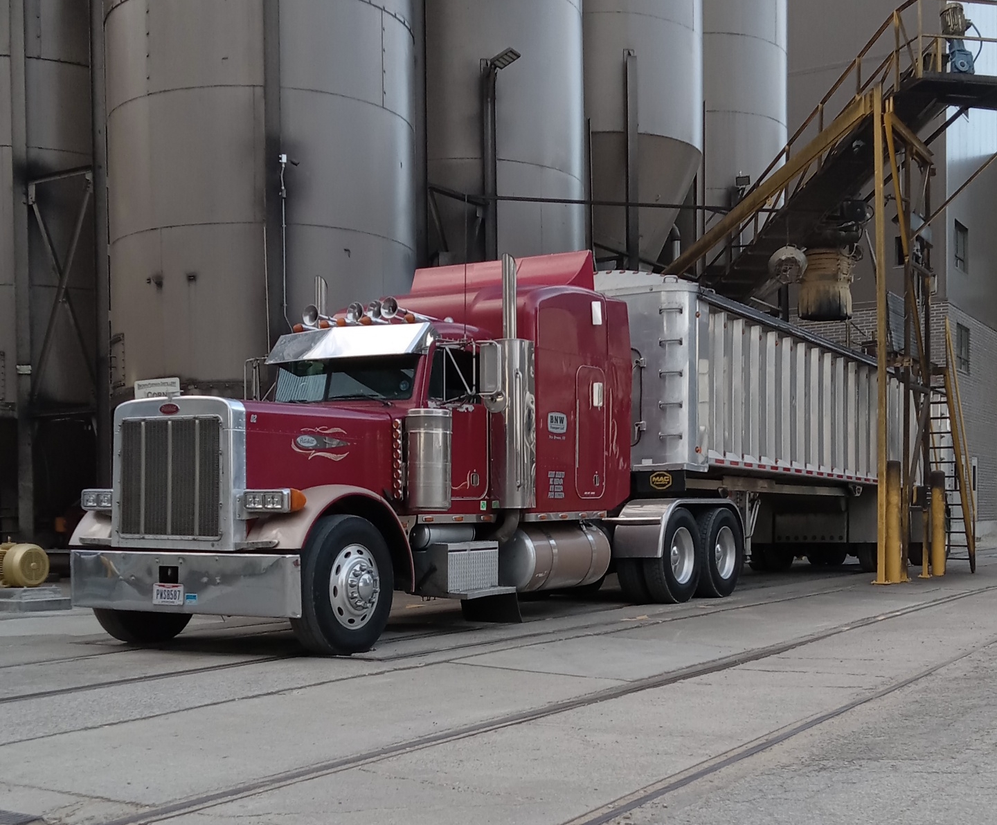 Red semi-truck parked at industrial facility.